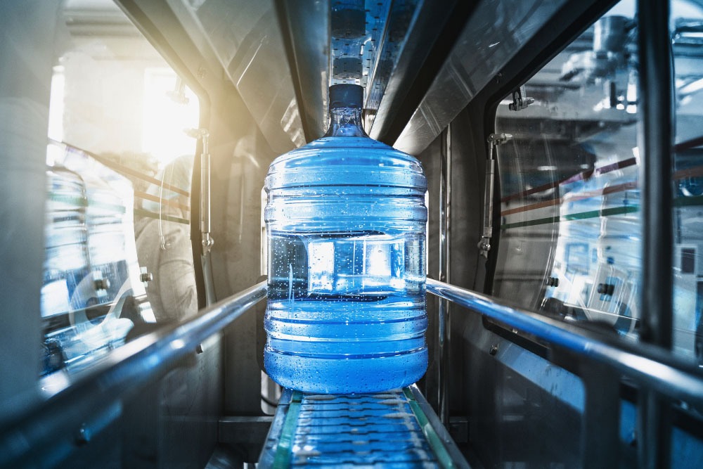 Plastic bottle or gallon of purified drinking water inside automated conveyor production line. Water factory, toned